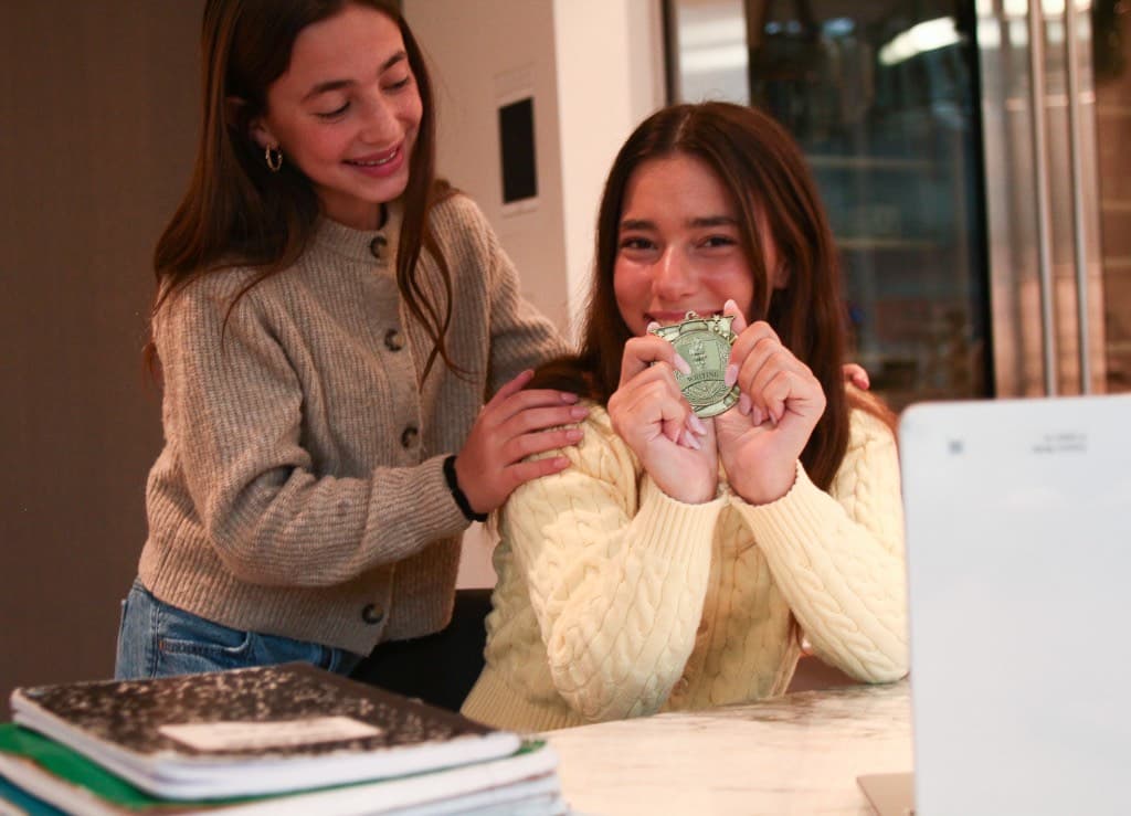 Two students celebrating a writing medal at a study table