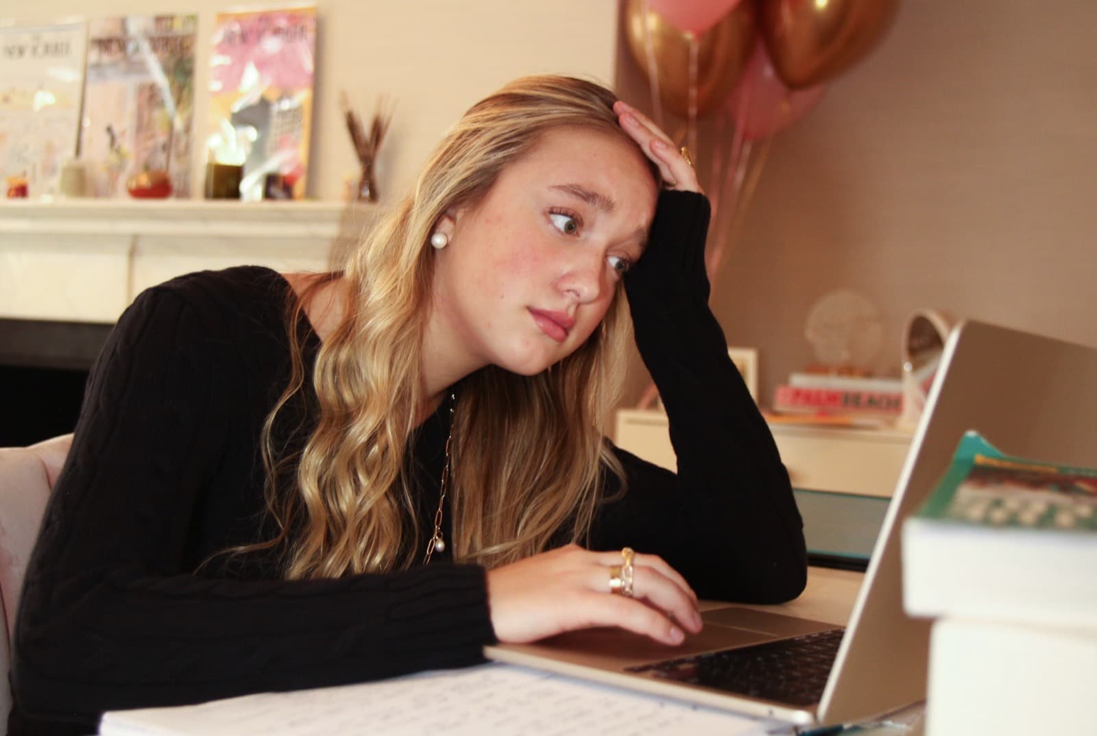 High school student looking overwhelmed while working on a laptop and school papers